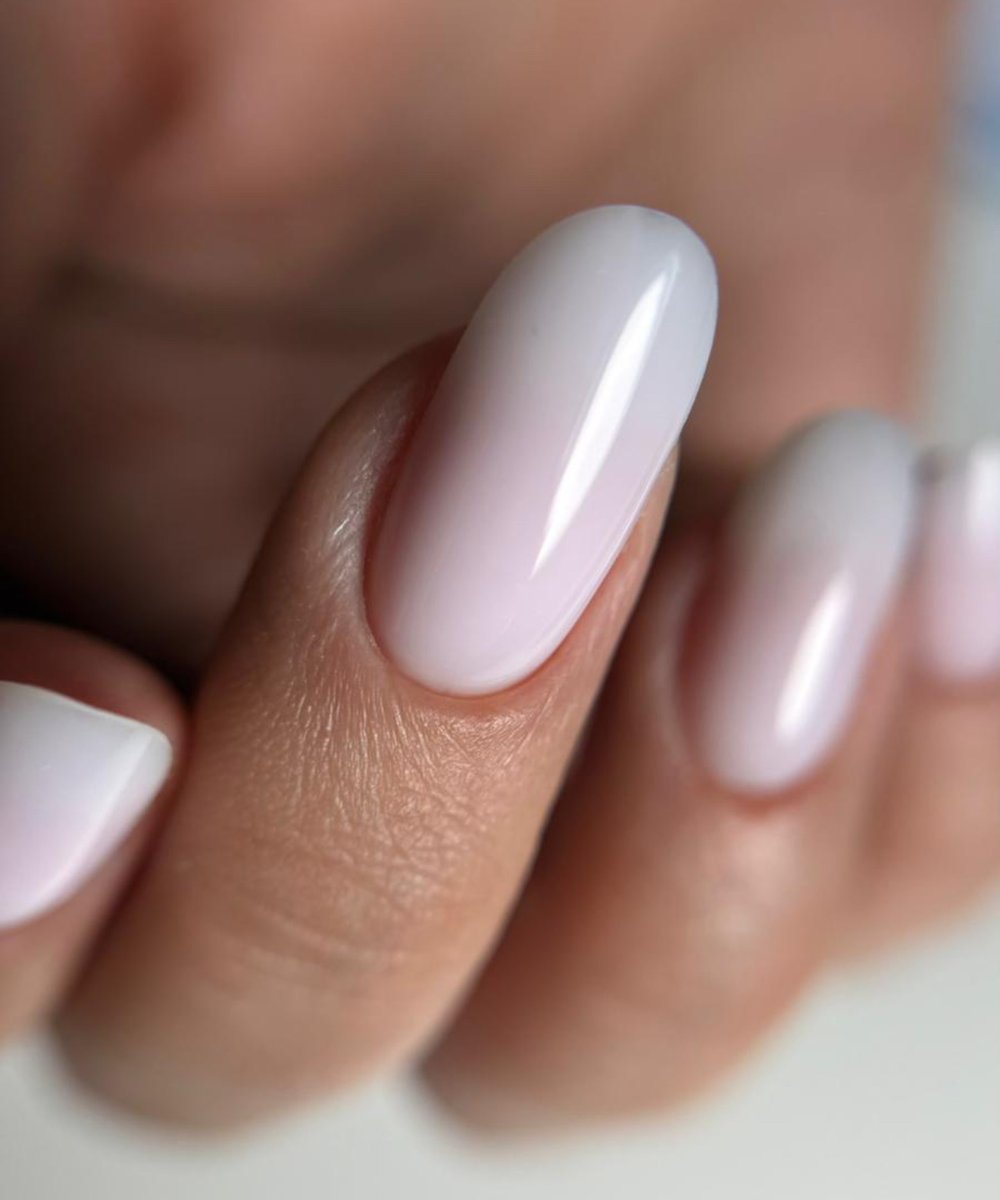 Gros plan sur des ongles en amande nude laiteux